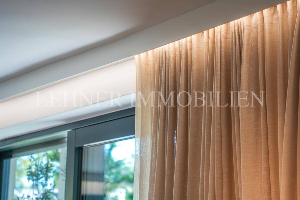 Detailansicht eines Fensters mit eleganten Vorhängen und indirekter Deckenbeleuchtung.