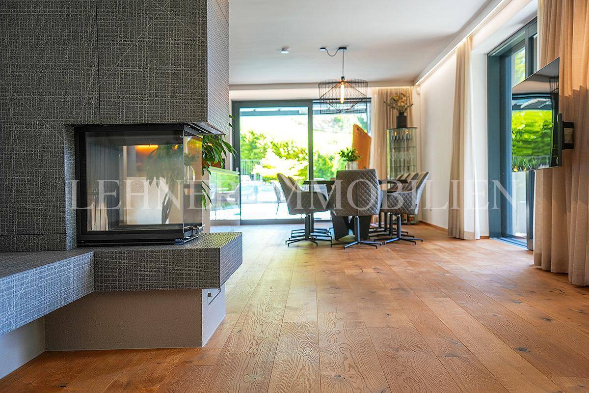 Heller Wohn- und Essbereich mit modernem Kamin, Holzboden und Zugang zur Terrasse.