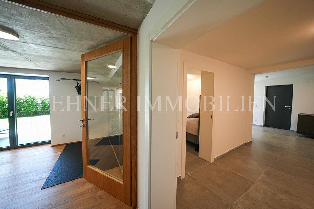 Heller Flur mit Holztür und Glasfront, der zu weiteren Räumen führt.
