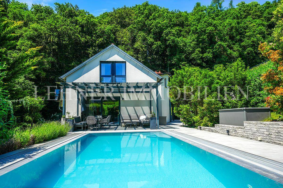 Sonniger Außenbereich mit großem Swimmingpool, Whirlpool und überdachter Terrasse.