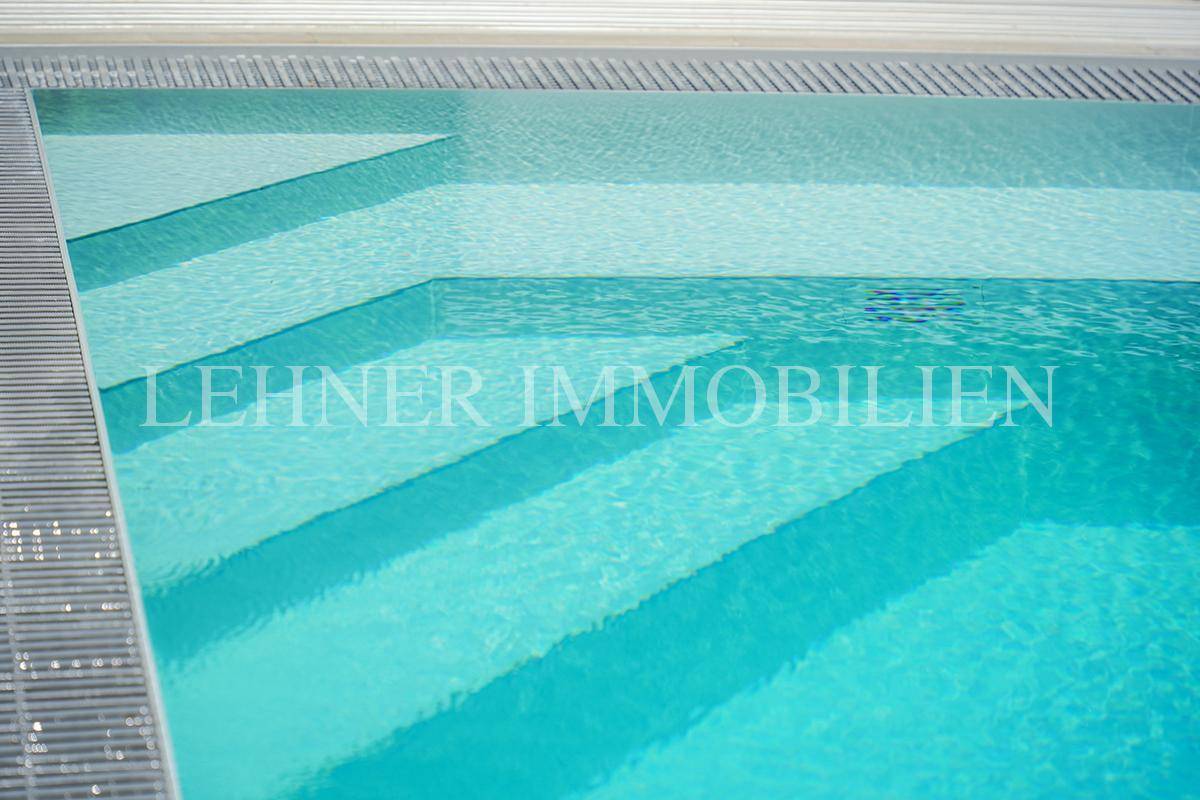 Detailaufnahme der eleganten Stufen, die in den klaren Swimmingpool führen.