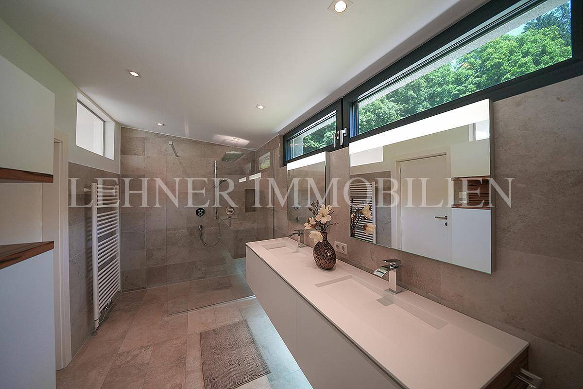 Geräumiges modernes Badezimmer mit Doppelwaschbecken, begehbarer Dusche und breitem Fenster.