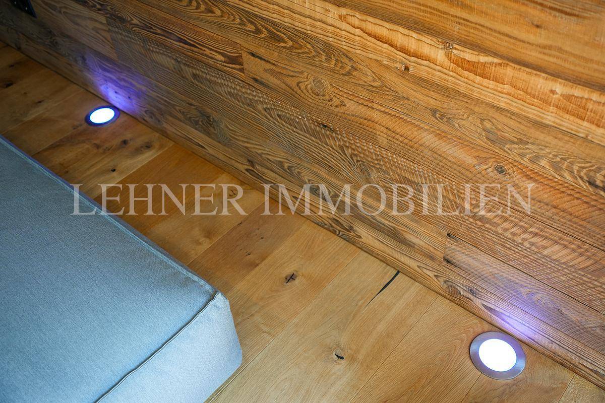 Detailaufnahme von Holzboden und Holzwand mit integrierter Bodenbeleuchtung.