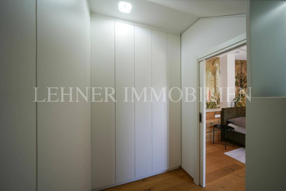 Praktischer Ankleidebereich mit weißen Einbauschränken und hellem Holzfußboden, angrenzend an das Schlafzimmer.