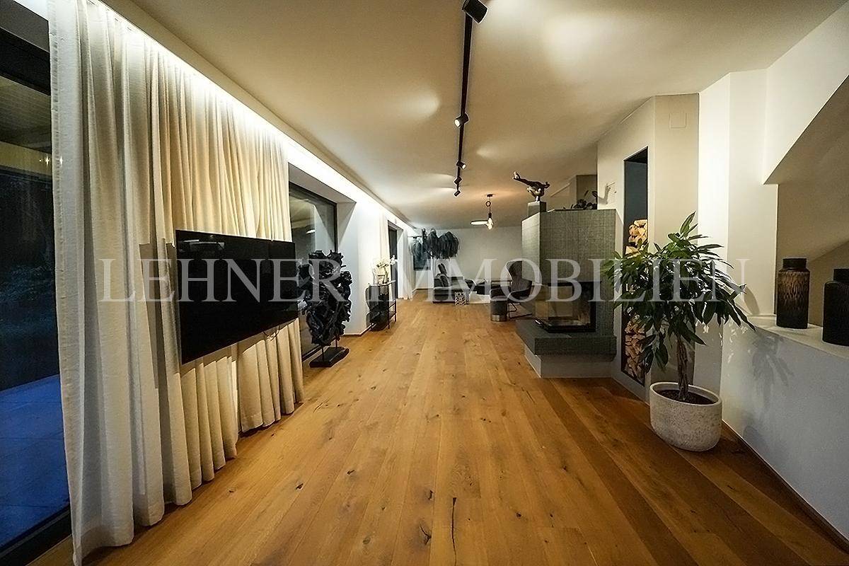 Geräumiges Wohnzimmer mit Holzboden, modernem Kamin und großem Flachbildfernseher.