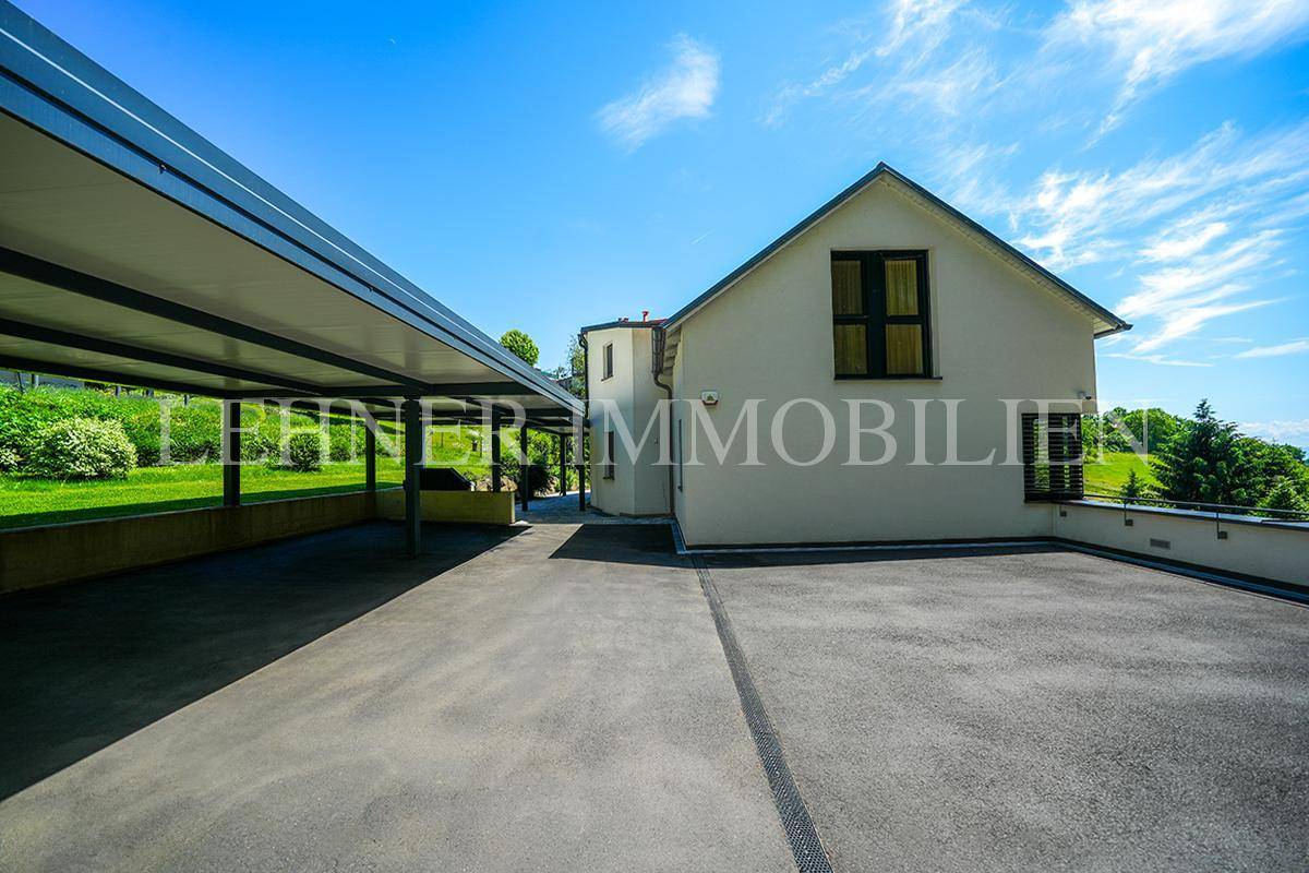 Ansicht des Hauses mit großem gepflasterten Parkplatz und modernem Carport.