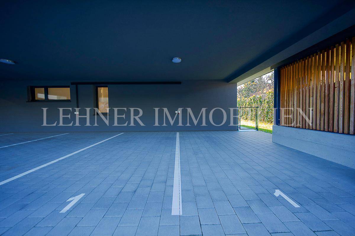 Überdachter Parkbereich mit markierten Stellplätzen, bietet Schutz für Fahrzeuge.