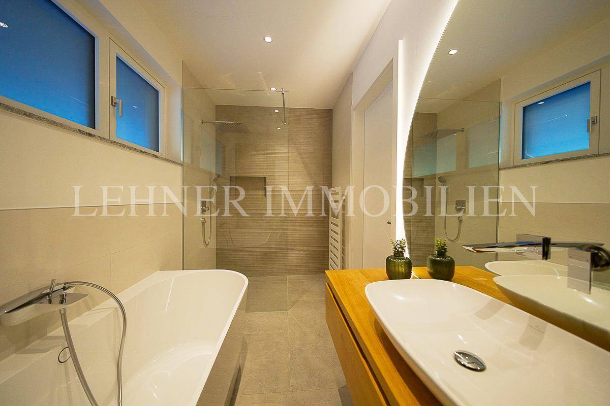 Modernes Badezimmer mit Badewanne, begehbarer Dusche und Doppelwaschbecken auf Holzunterschrank.