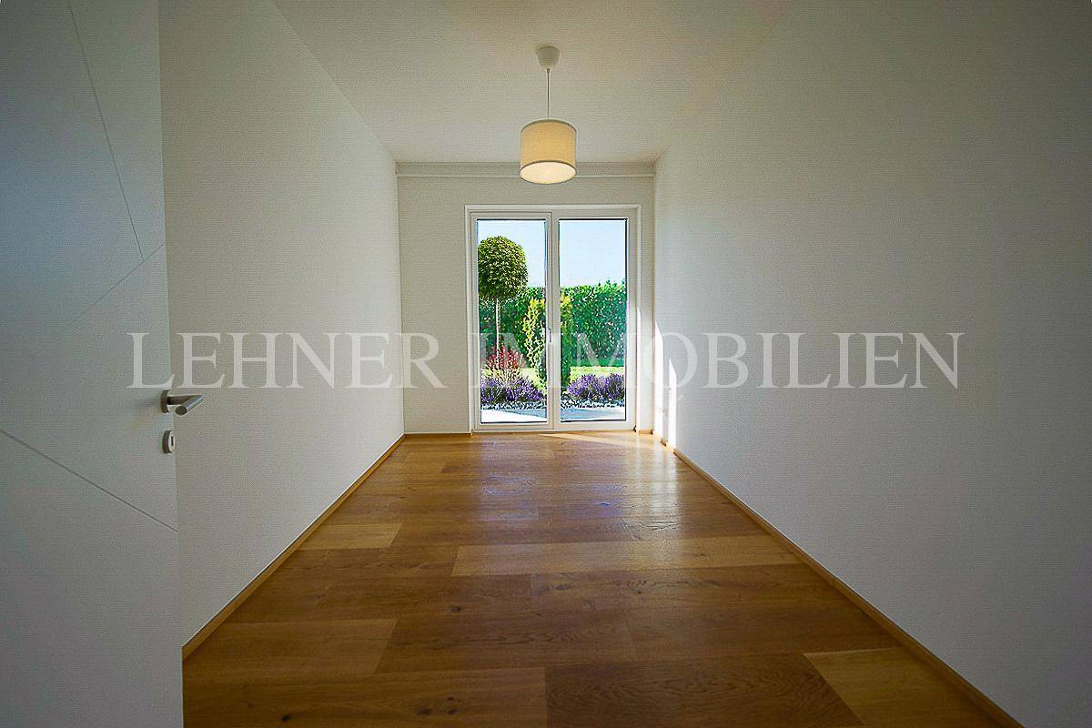 Heller Raum mit Holzboden und Zugang zu einem kleinen Gartenbereich, ideal für verschiedene Nutzungen.