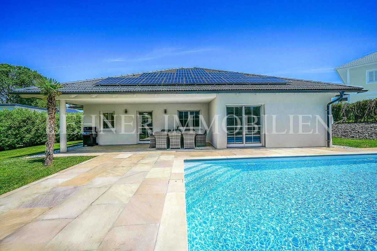 Modernes Haus mit großem Pool, Sonnenterrasse und Photovoltaikanlage auf dem Dach.