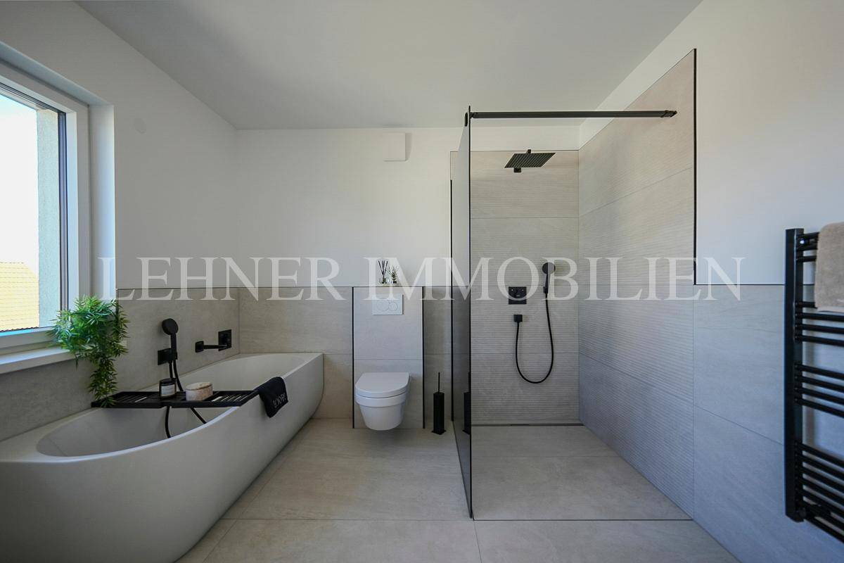 Elegantes Badezimmer mit freistehender Badewanne, bodengleicher Dusche und modernen Armaturen.