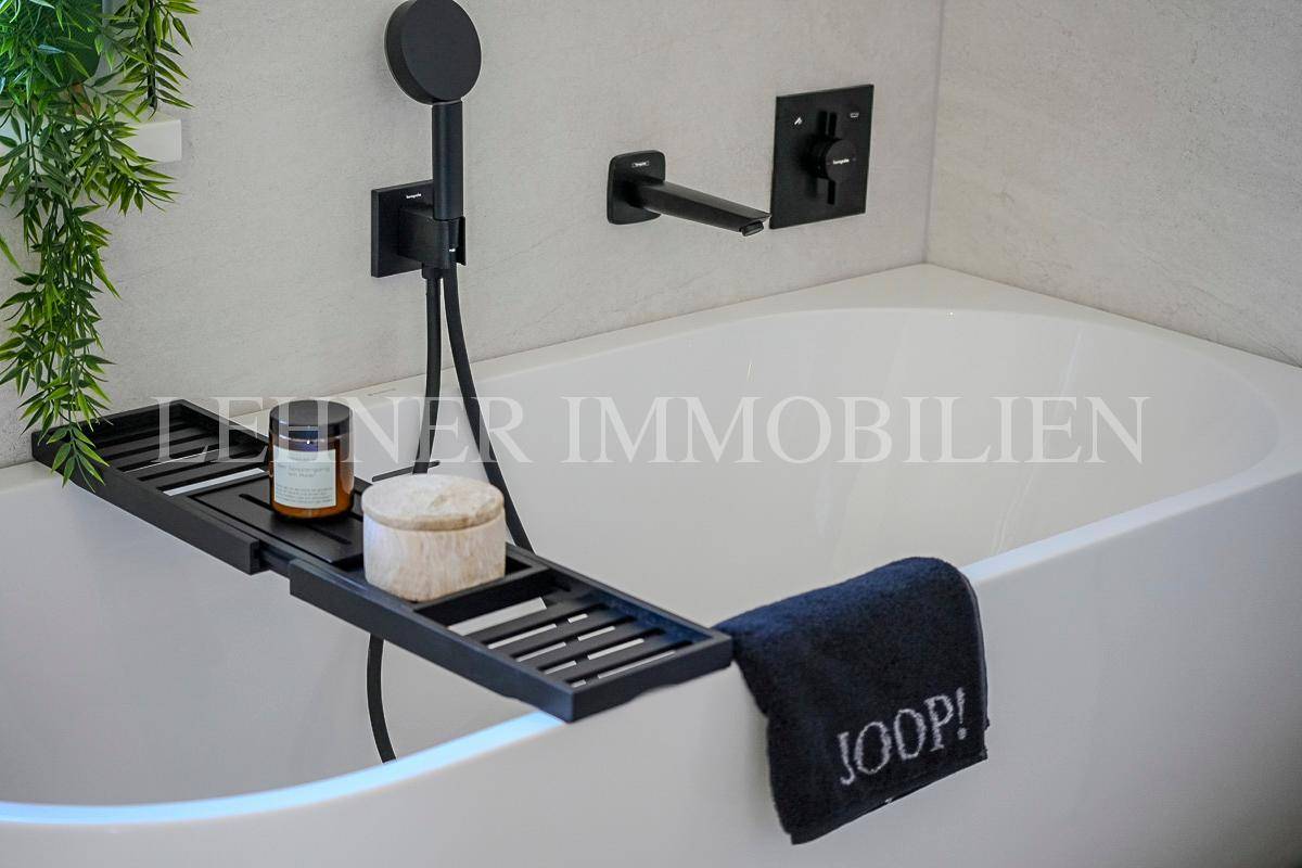 Detailansicht der Badewanne mit schwarzem Badewannenbrett und moderner Handbrause.