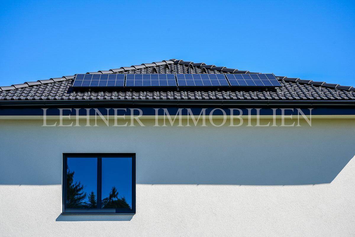 Dach des Hauses mit integrierten Photovoltaik-Modulen zur nachhaltigen Energiegewinnung und einem Fenster darunter.