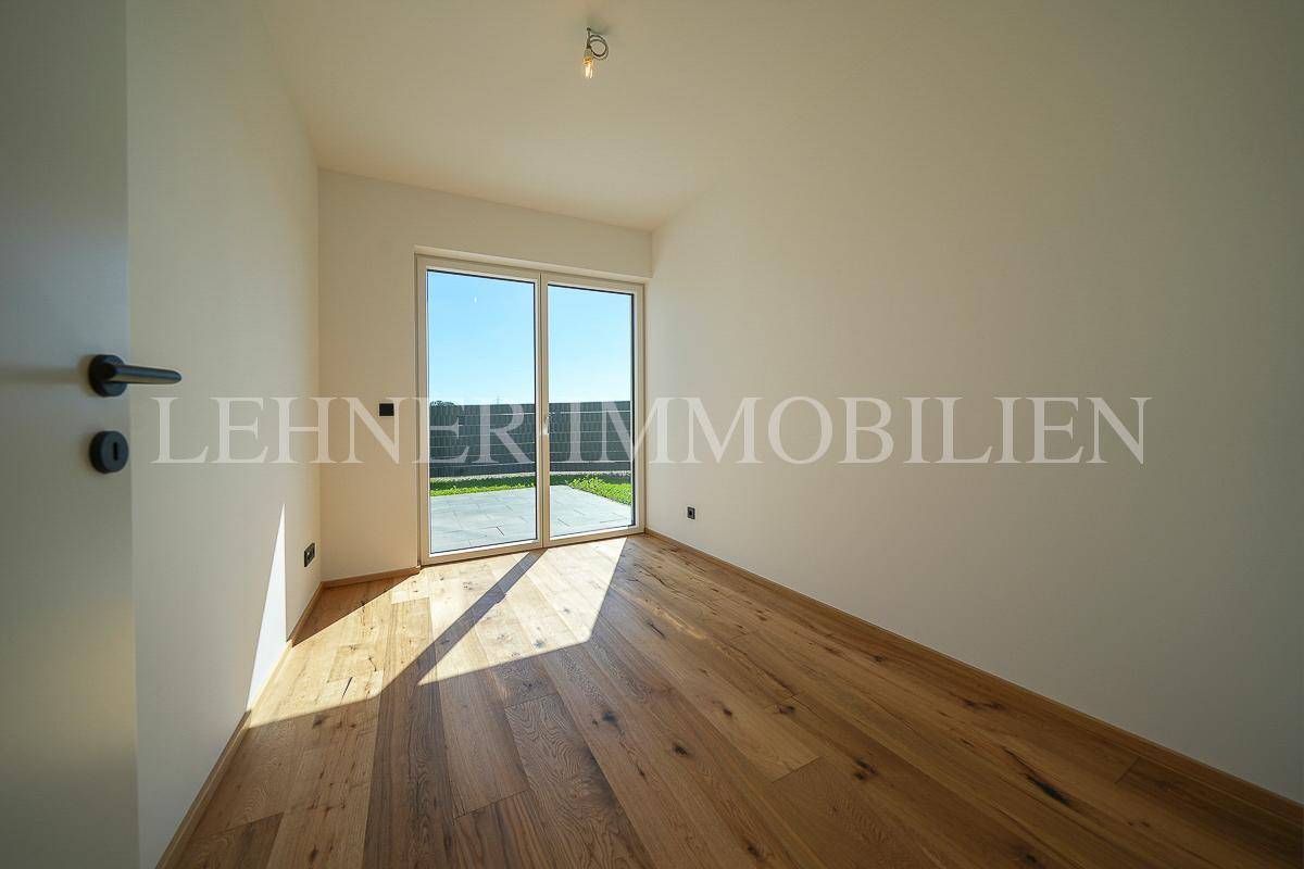 Lichtdurchflutetes Zimmer mit Holzboden und Blick ins Grüne, ideal als Schlaf- oder Arbeitszimmer nutzbar.