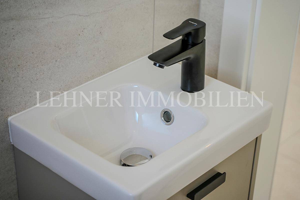 Nahaufnahme des modernen Waschbeckens mit schwarzem Wasserhahn im Gäste-WC.
