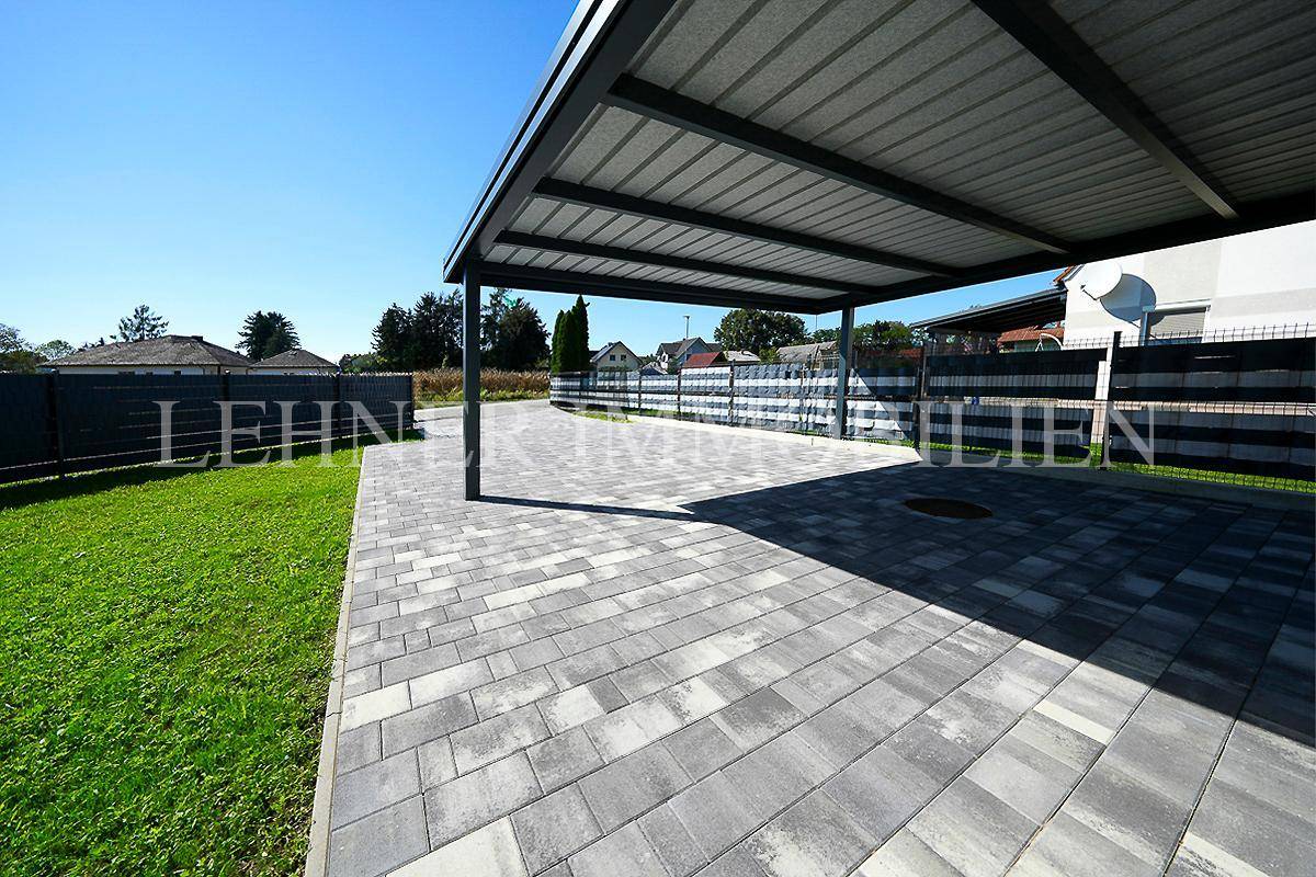 Weitläufiger, gepflasterter Bereich unter dem Carport, bietet ausreichend Platz für mehrere Fahrzeuge.