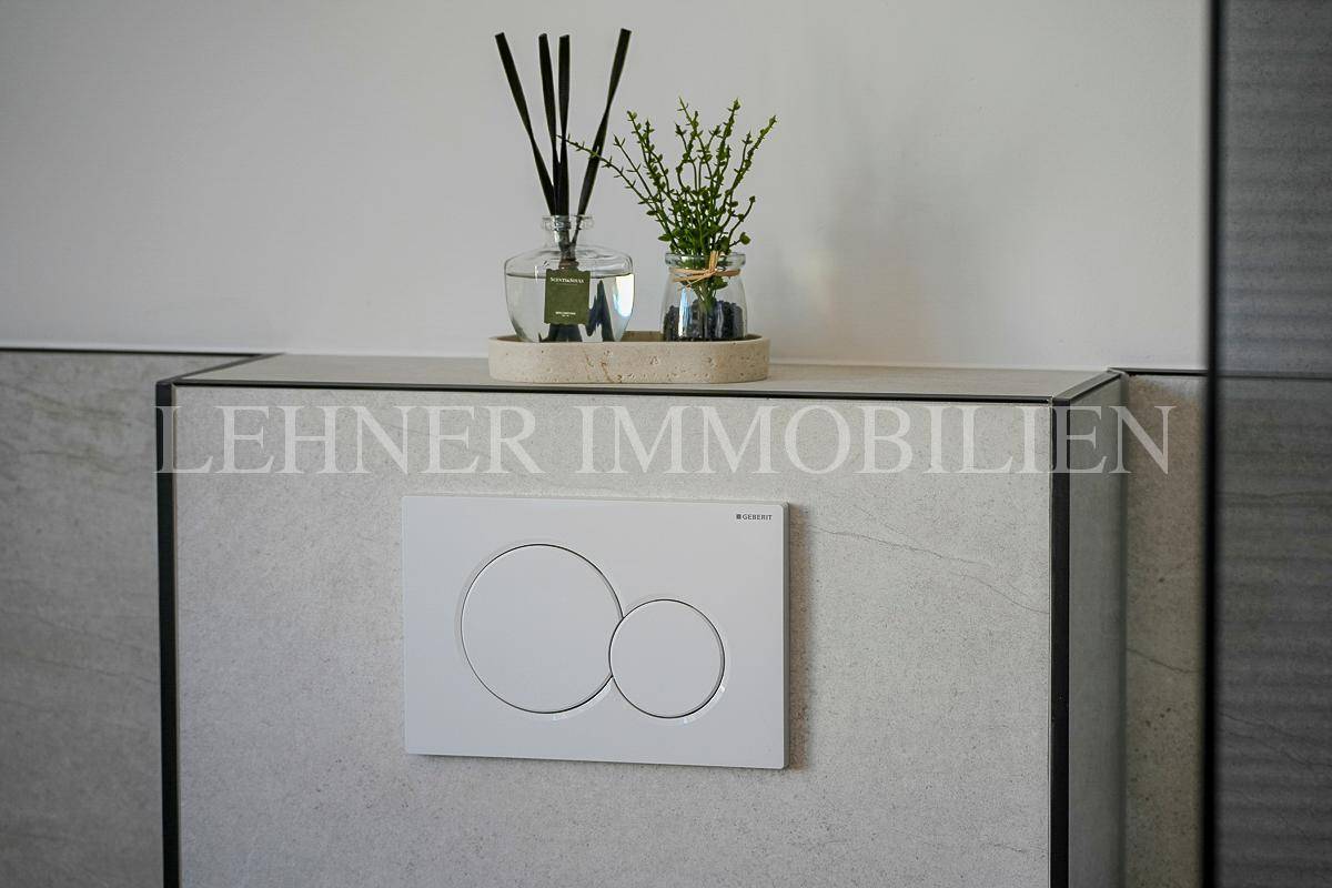 Moderne Toilettenspülung mit stilvollen Dekorationen auf gefliester Ablage in einem Badezimmer.