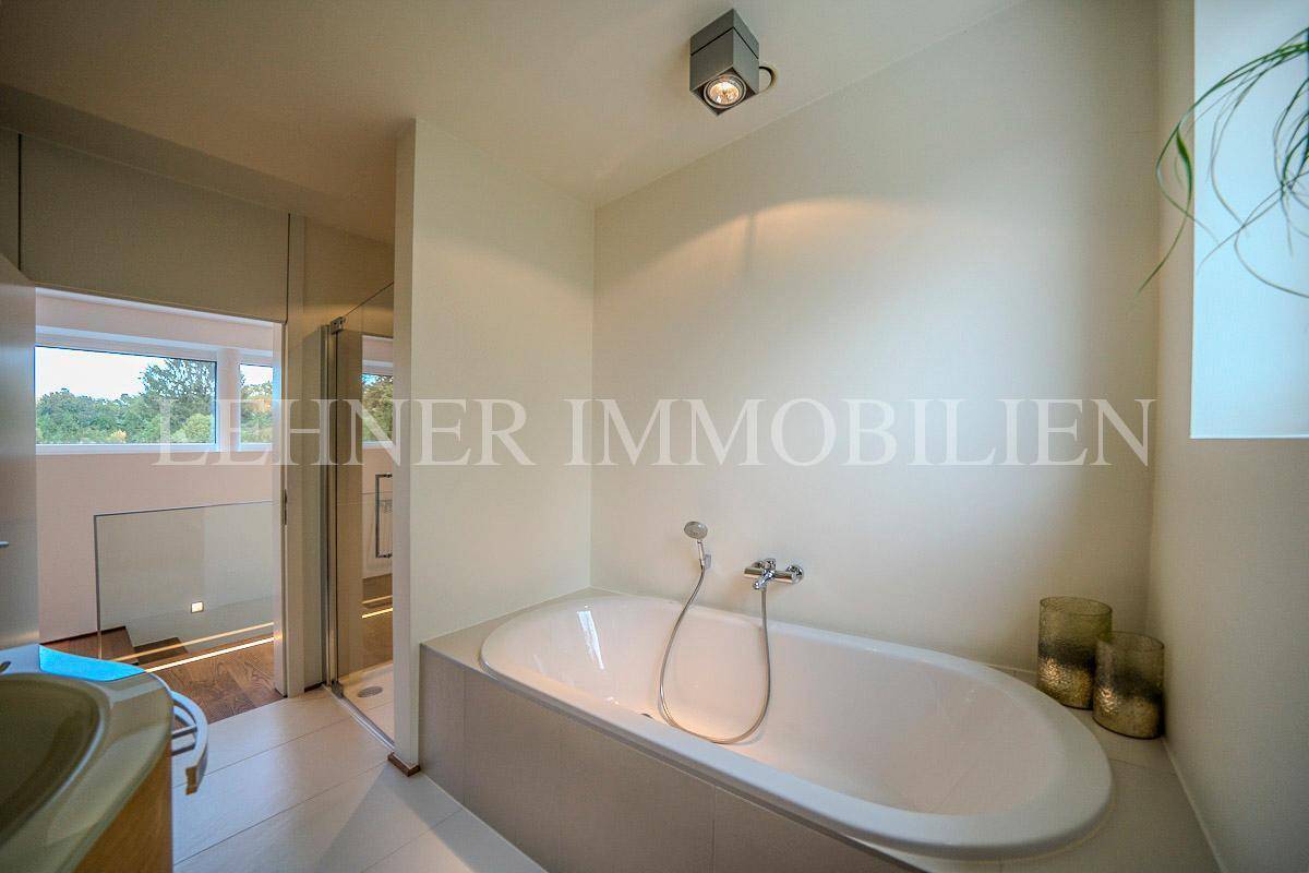 Helles Badezimmer mit eingebauter Badewanne und Blick auf den Außenbereich.