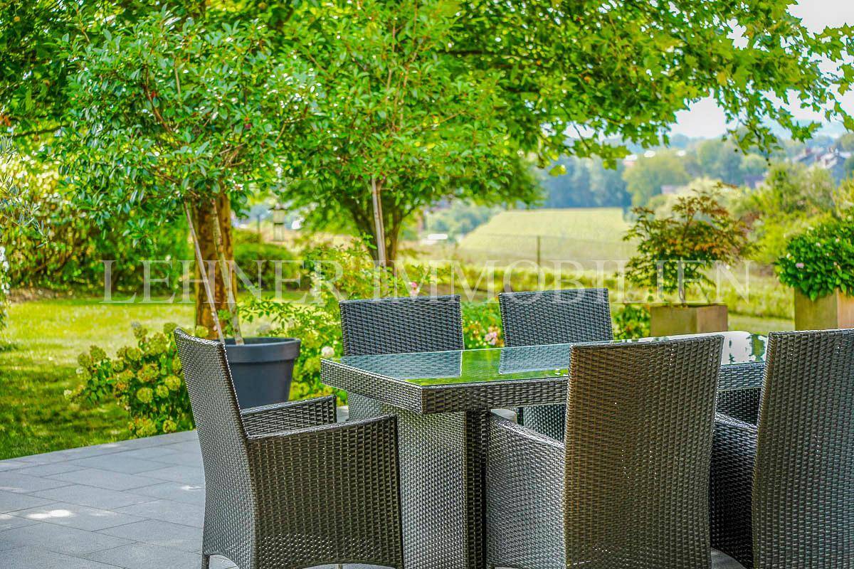 Gemütlicher Essbereich im Garten mit Blick auf die grüne Landschaft und alte Bäume.