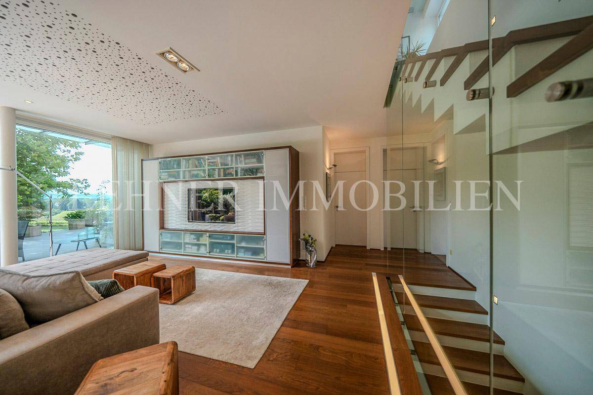 Helles Wohnzimmer mit Holzboden, integriertem Mediamöbel und Zugang zur Terrasse.