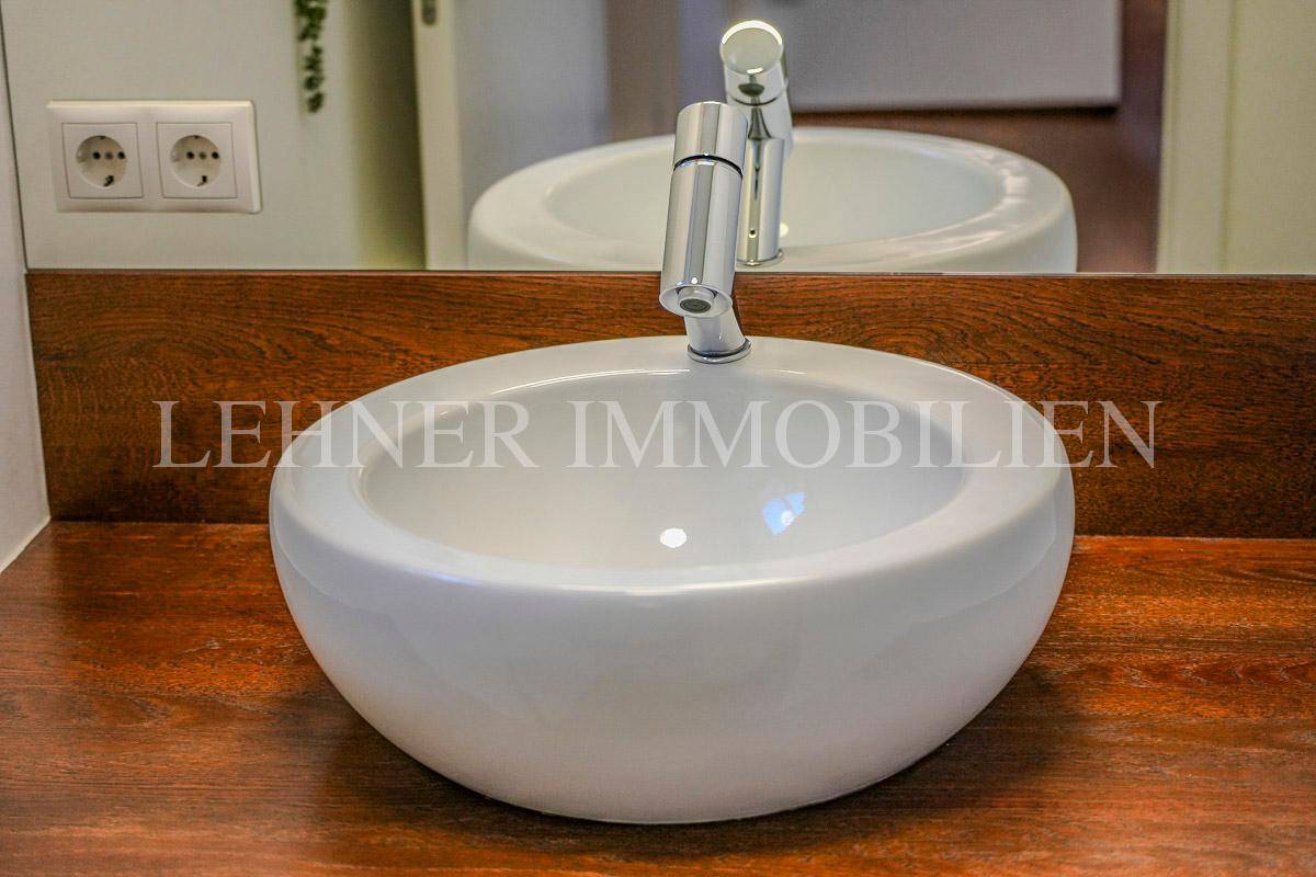 Detailaufnahme des modernen Aufsatzwaschbeckens mit Holzarbeitsplatte im Gäste-WC.