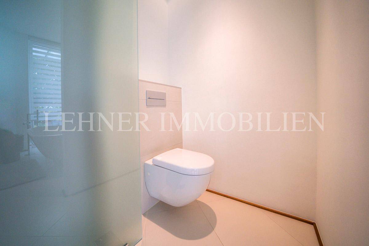 Modernes Gäste-WC mit wandhängendem WC und hellen Fliesen.
