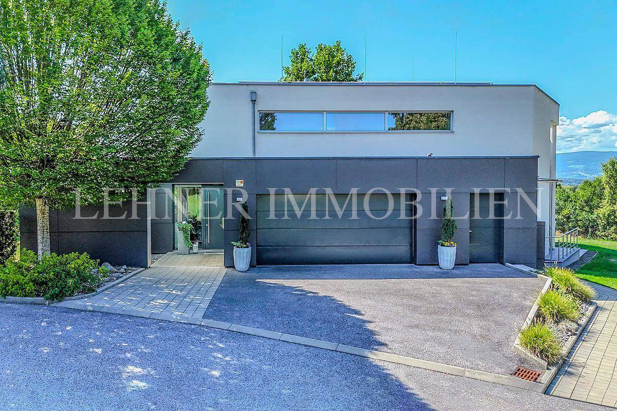 Moderne Hausfront mit integrierter Doppelgarage und gepflastertem Zugangsbereich.