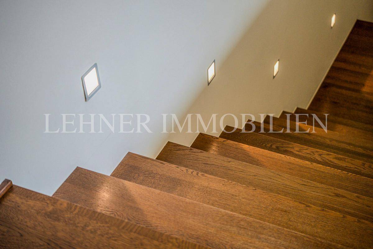 Elegante Holztreppe mit integrierter Wandbeleuchtung, die für eine angenehme Atmosphäre sorgt.