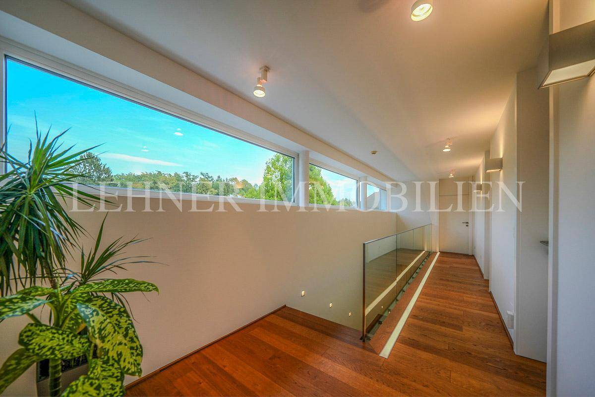 Heller Flur im Obergeschoss mit langen Panoramafenstern und elegantem Holzparkettboden.