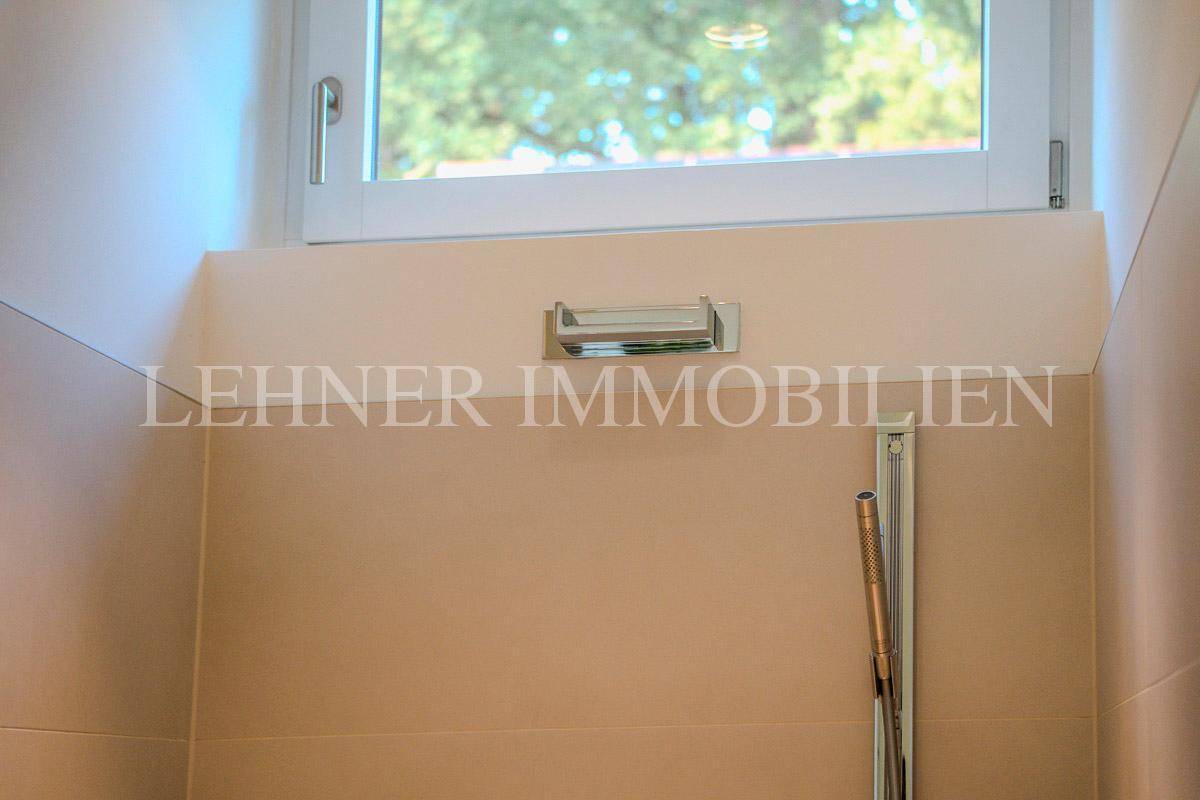 Detailansicht des Duschbereichs mit Fenster und moderner Armatur.