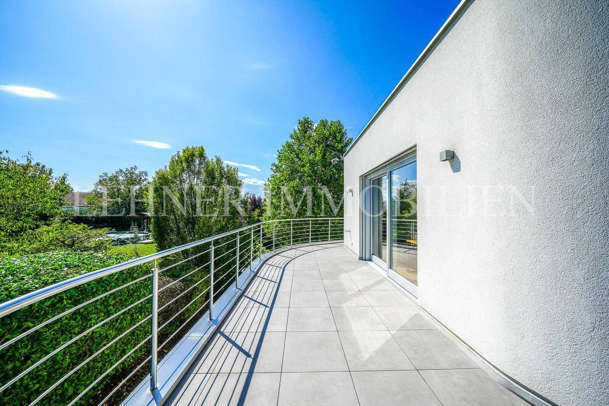 Großer, geschwungener Balkon mit modernem Metallgeländer und weitem Blick ins Grüne.