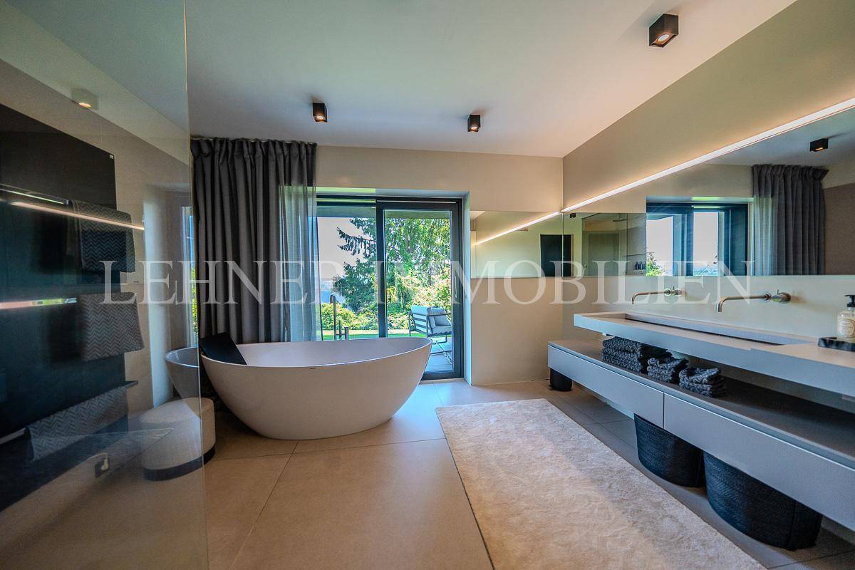 Luxuriöses Badezimmer mit freistehender Badewanne, Doppelwaschbecken und Zugang zum Garten.