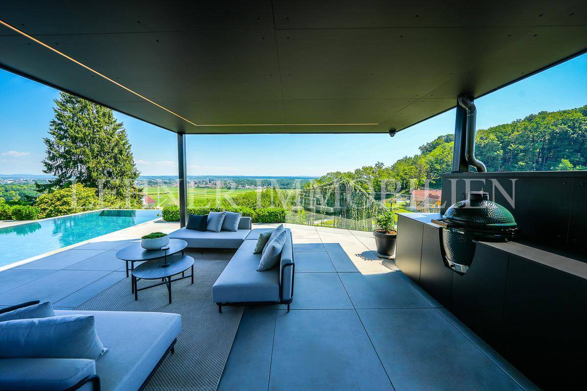 Geräumige Terrasse mit Infinity-Pool, Lounge-Bereich und integrierter Außenküche mit Grill.
