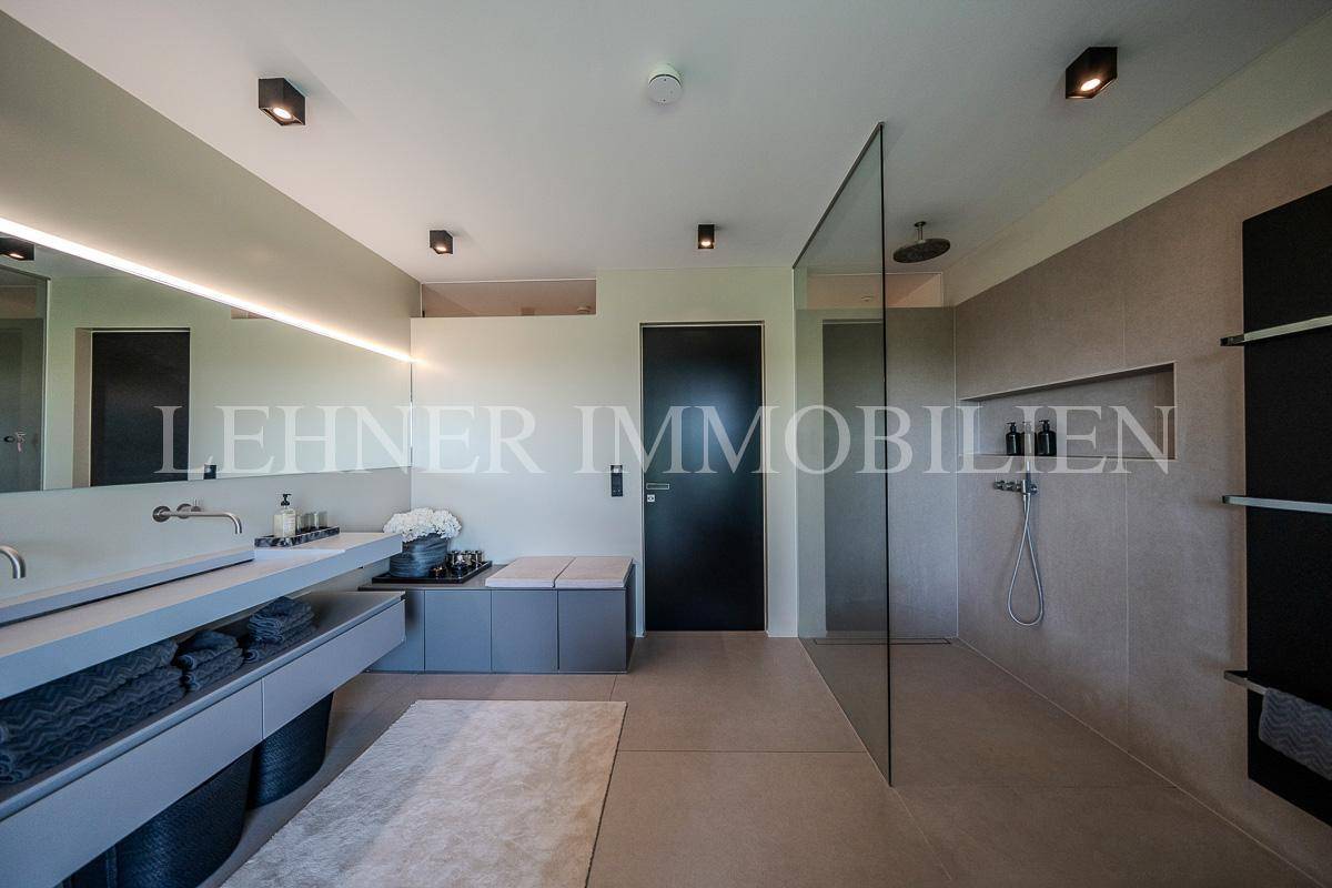 Modernes Badezimmer mit großer begehbarer Dusche, Doppelwaschbecken und eleganten Fliesen.
