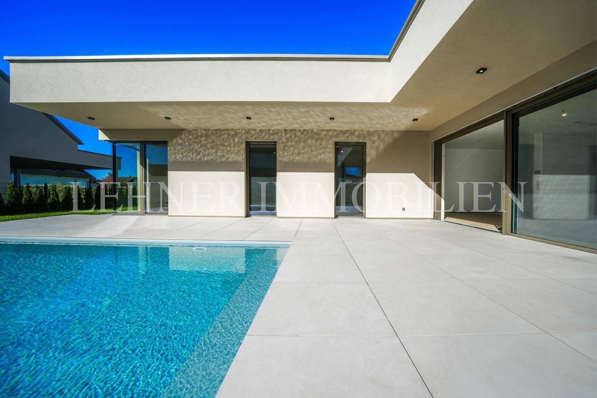 Großzügige Poolterrasse mit klarem Wasser und moderner Architektur des Hauses an einem sonnigen Tag.
