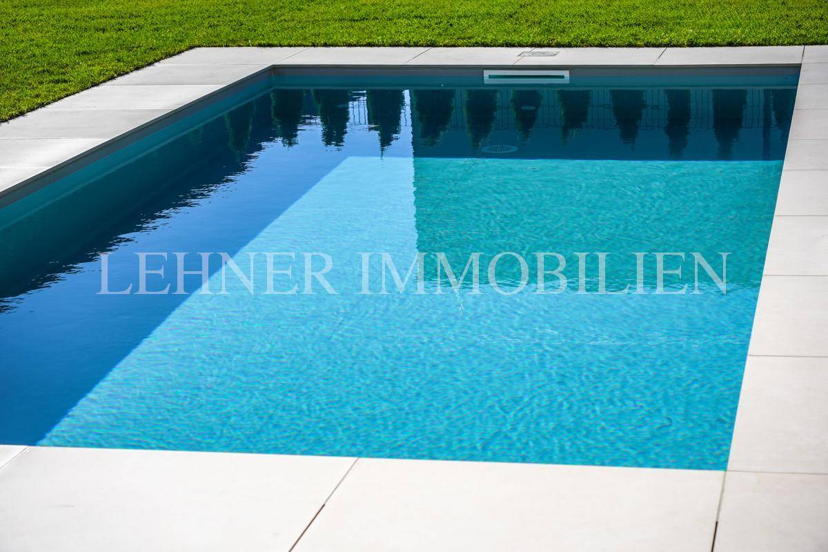 Sauberer, rechteckiger Swimmingpool mit hellen Fliesen und umgebender Rasenfläche.
