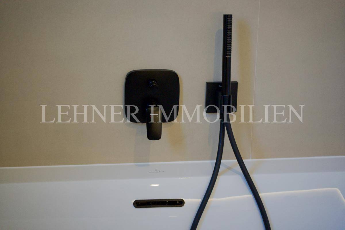Nahaufnahme der schwarzen Badewannenarmatur und Handbrause im modernen Badezimmer.