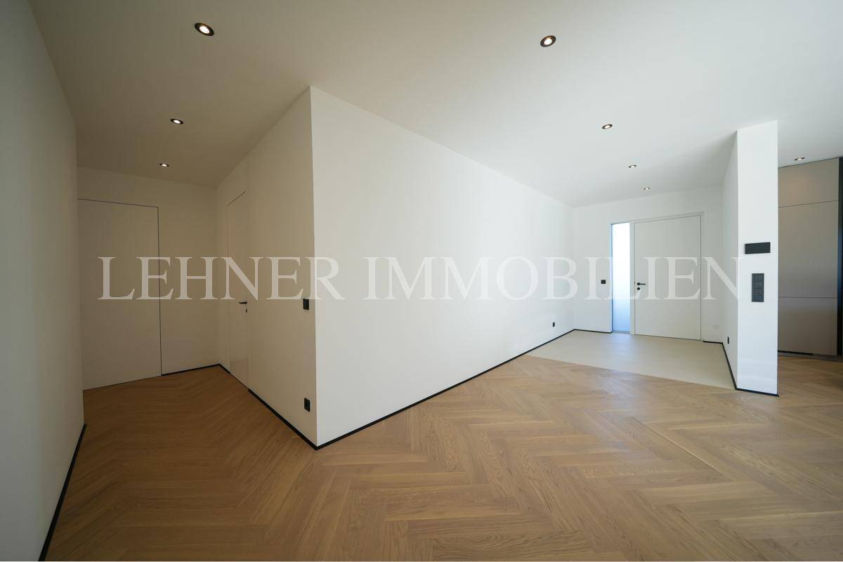 Heller Flur mit Fischgrätparkett und minimalistischen weißen Wänden.