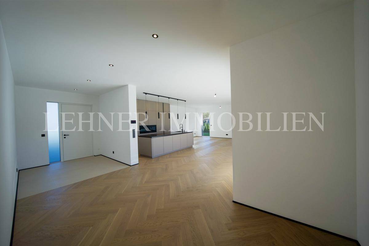 Geräumiger, offener Wohnbereich mit Holzboden und Blick auf die moderne Küche.