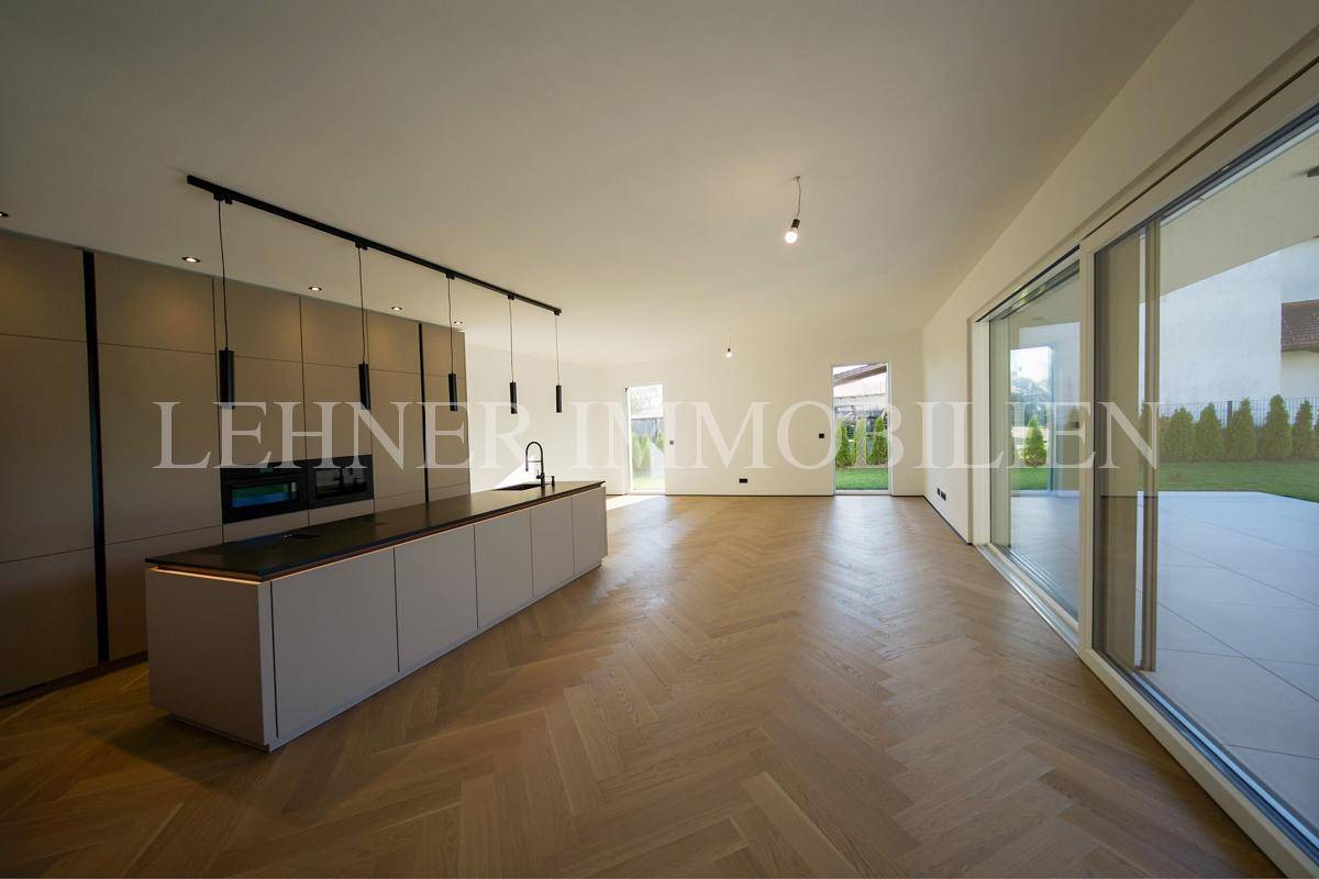 Weitläufiger offener Küchen- und Wohnbereich mit Holzboden und viel Tageslicht.