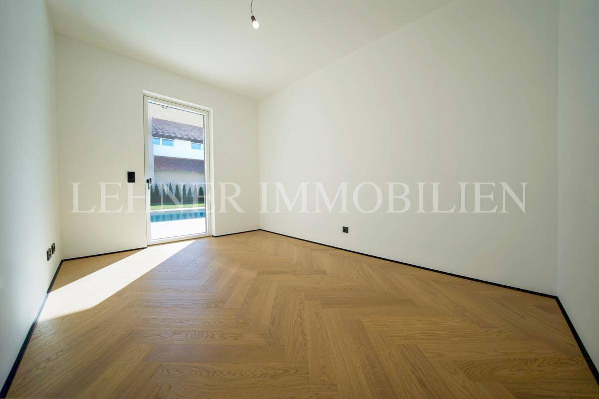 Helles Schlafzimmer mit Holzboden und Zugang zu einem Außenbereich mit Poolblick.