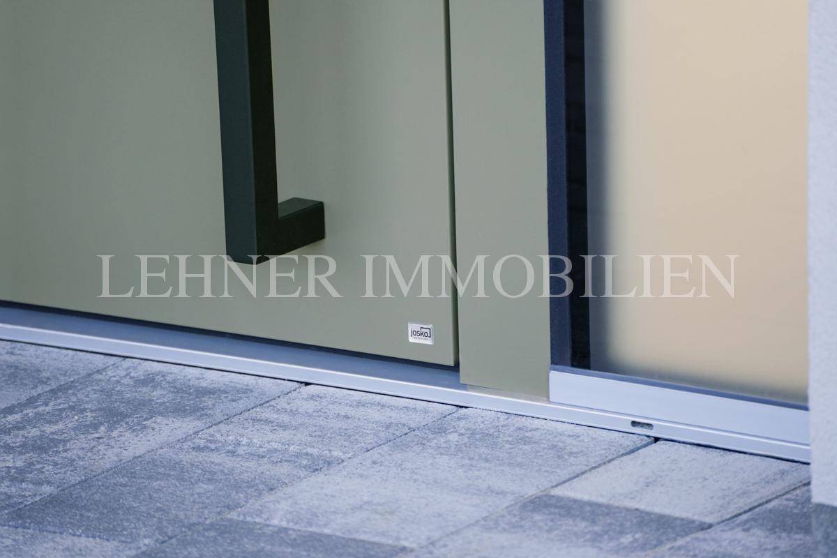 Detailansicht der modernen Türschwelle und des gepflasterten Eingangsbereichs.