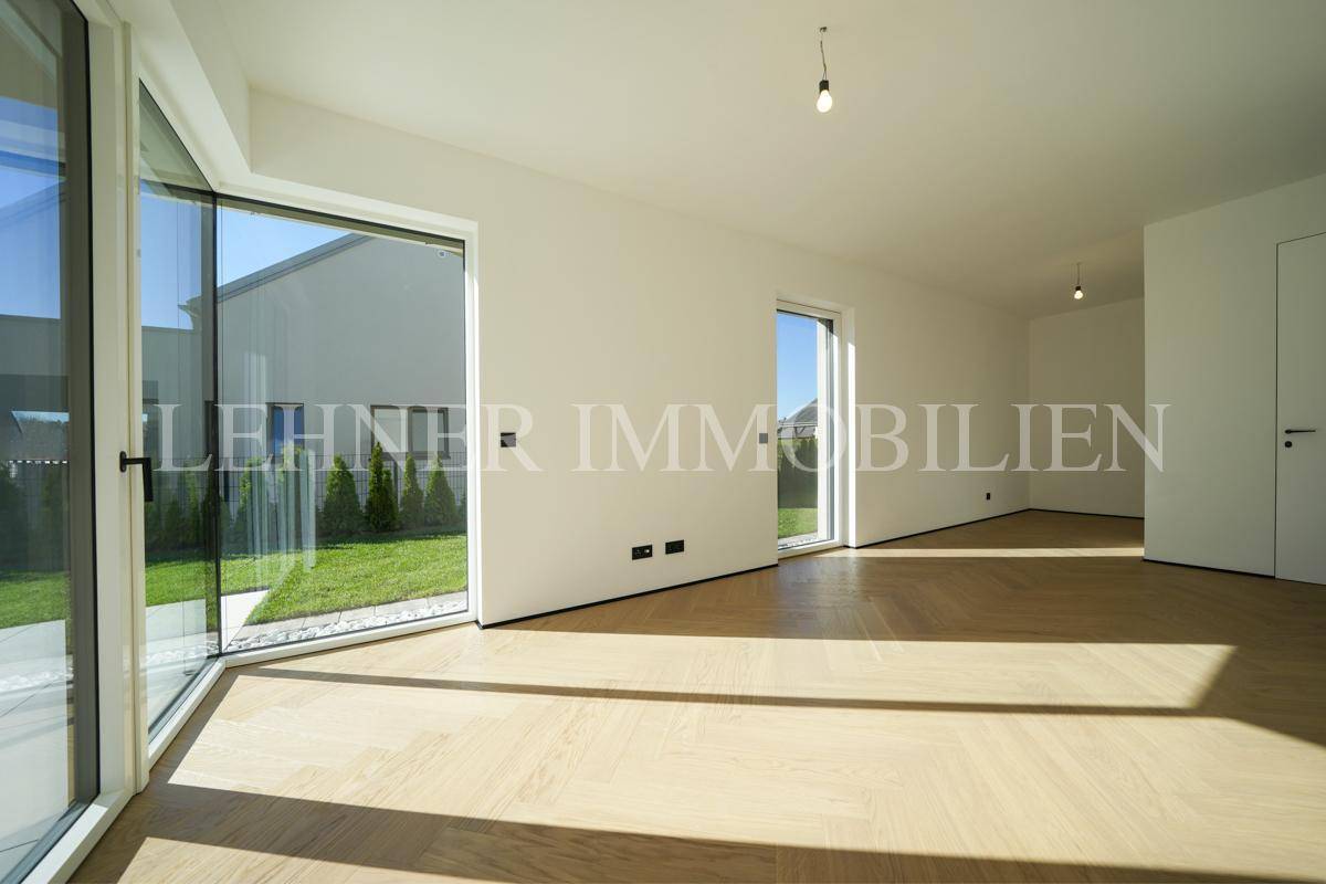 Lichtdurchfluteter Raum mit großen Fenstern und Holzboden, ideal für Wohn- oder Schlafzimmer.