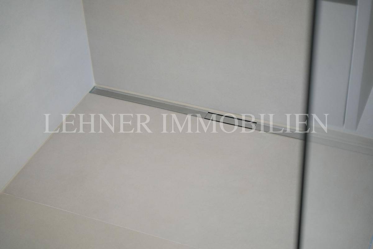 Detailansicht des modernen Duschbereichs mit minimalistischem Bodenablauf.