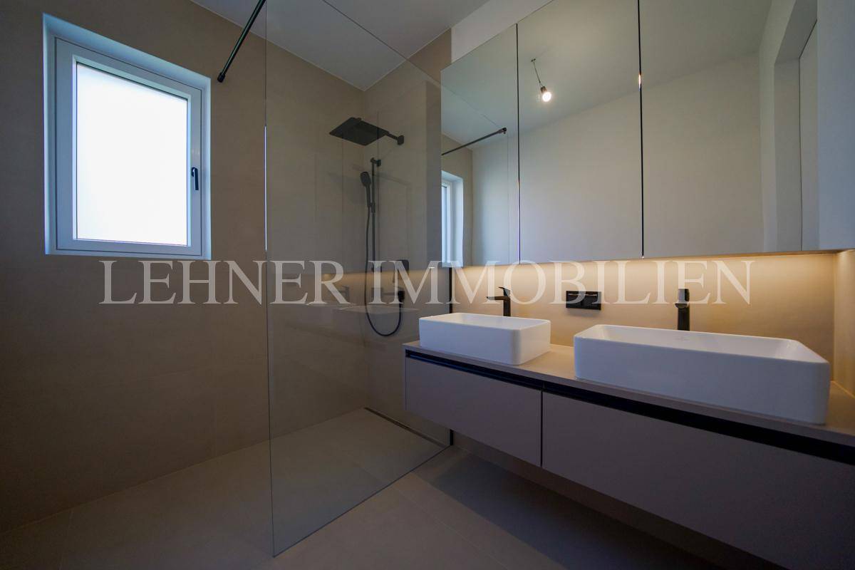 Modernes Badezimmer mit Doppelwaschbecken, großer begehbarer Dusche und Fenster.