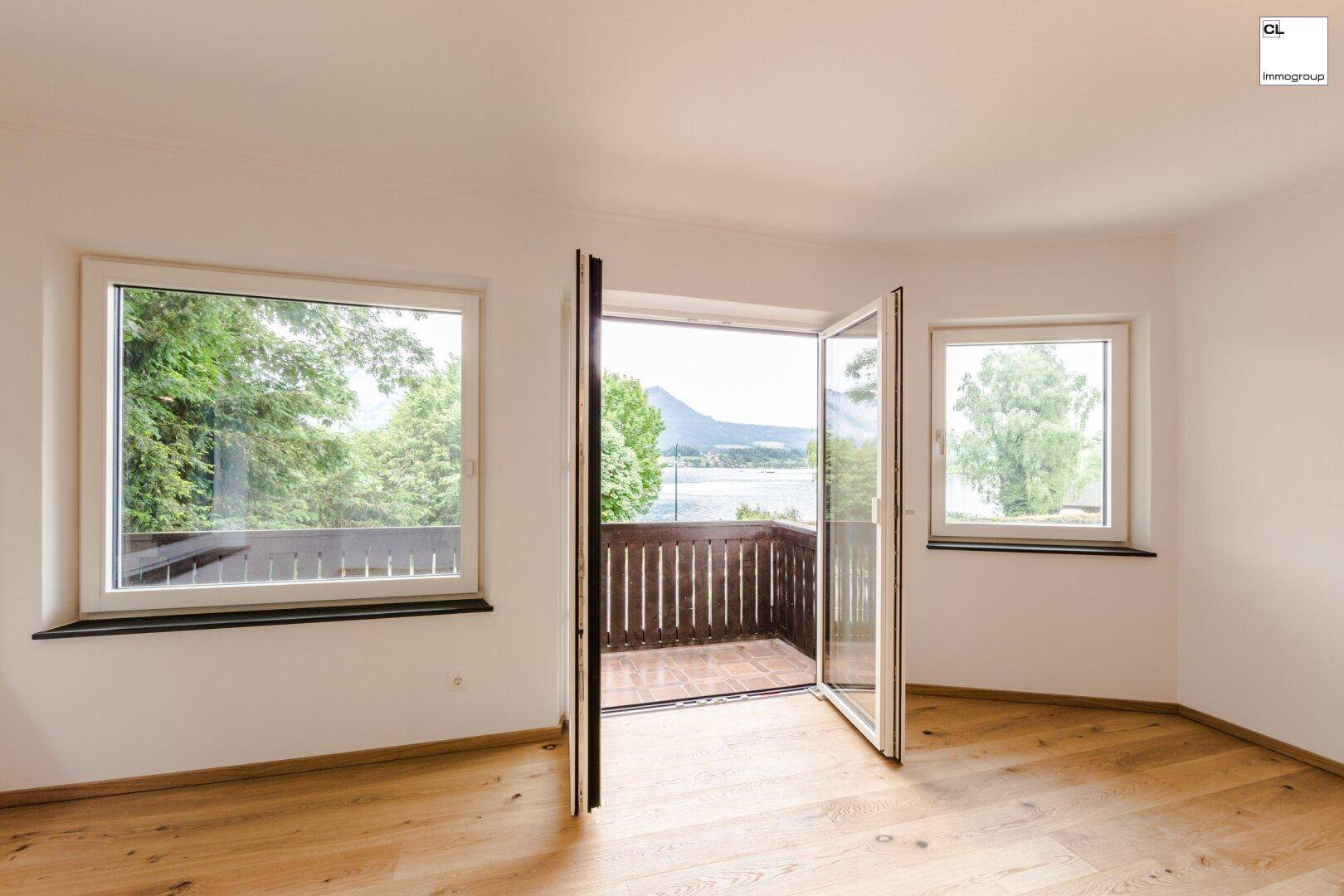 Heller Raum mit Holzboden und Zugang zu einem Balkon, bietet einen schönen Seeblick.