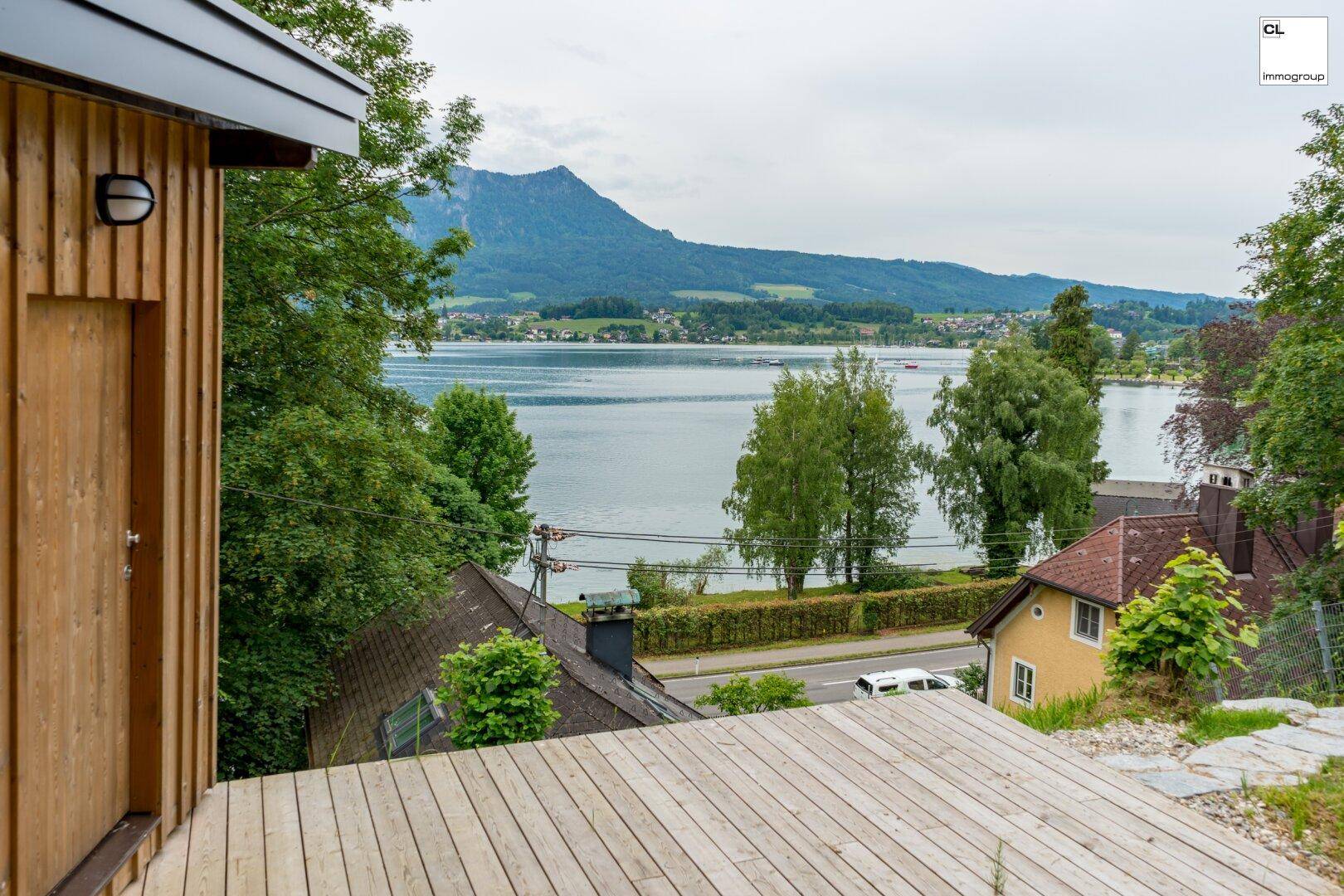 Große Holzterrasse mit weitem Blick auf den See und die umliegende Berglandschaft.