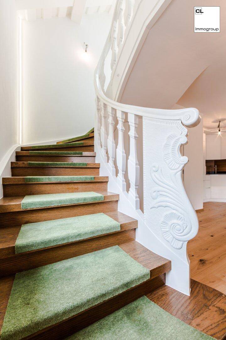 Elegante Holztreppe mit grünem Teppichläufer und kunstvoll geschnitztem Geländer.
