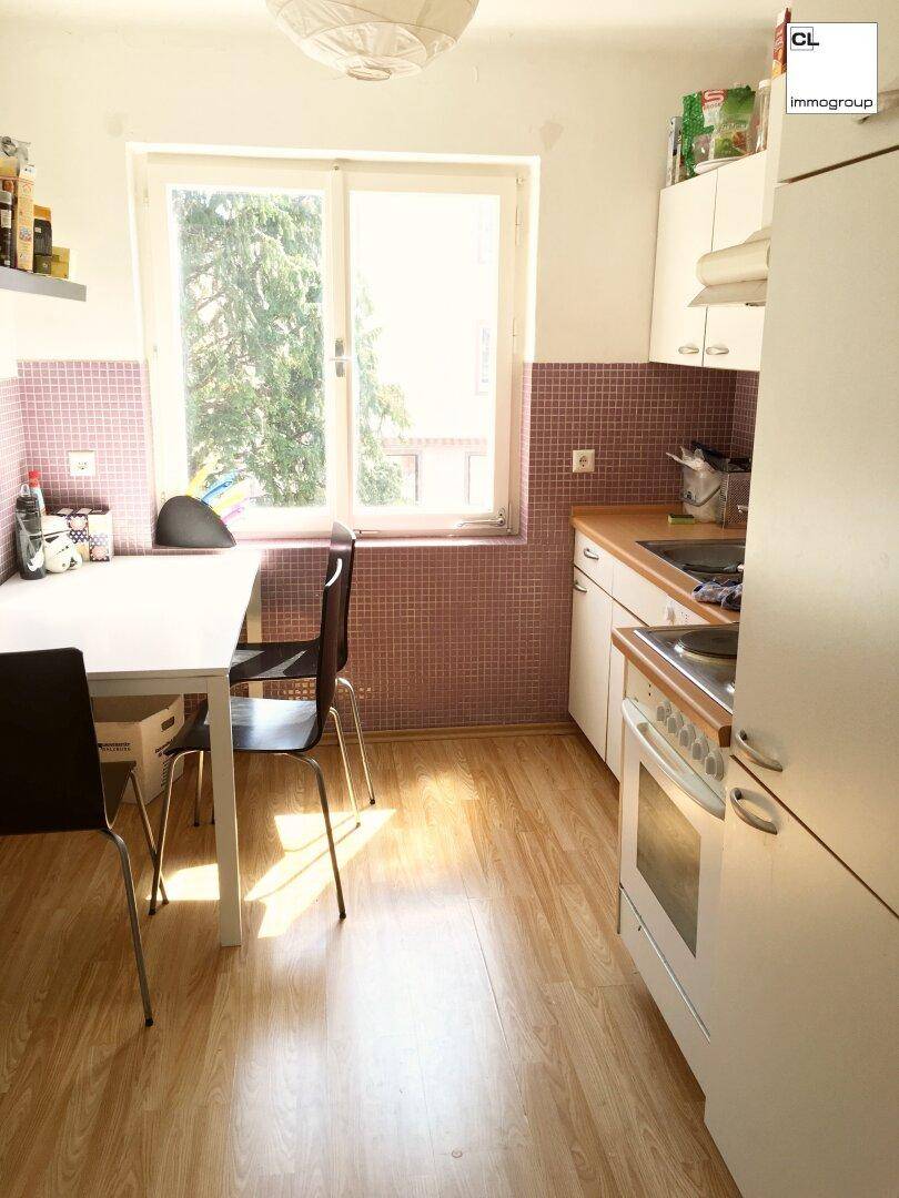 Funktionale Küche mit Essbereich, Fenster und rosa Fliesen, bietet Platz für Mahlzeiten.