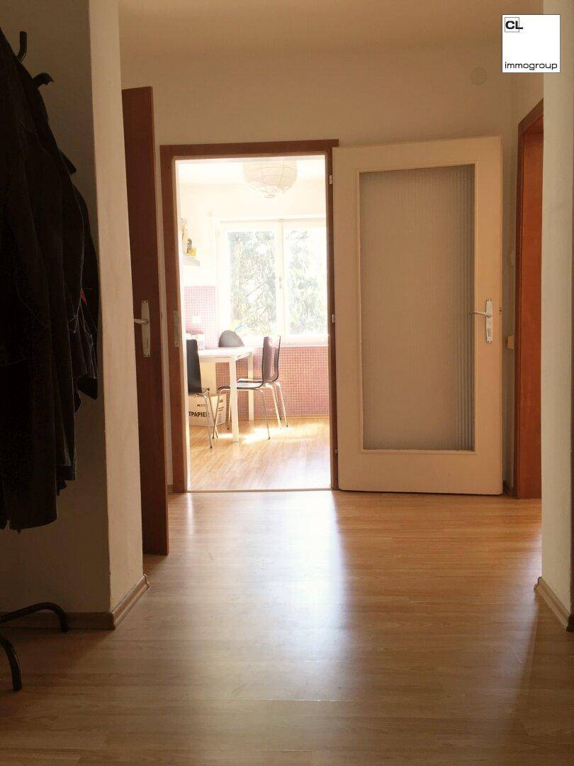 Heller Flur mit Laminatboden und Blick in die angrenzende Küche.